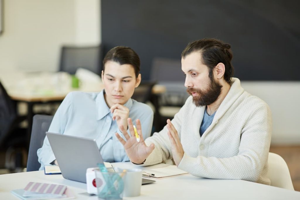 Branding digital et transformation numérique : deux spécialistes en stratégie de marque analysent des données sur un ordinateur portable lors d'une séance de travail collaborative